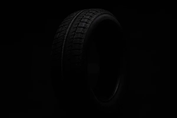 Black winter tire on a black background — Stock Photo, Image