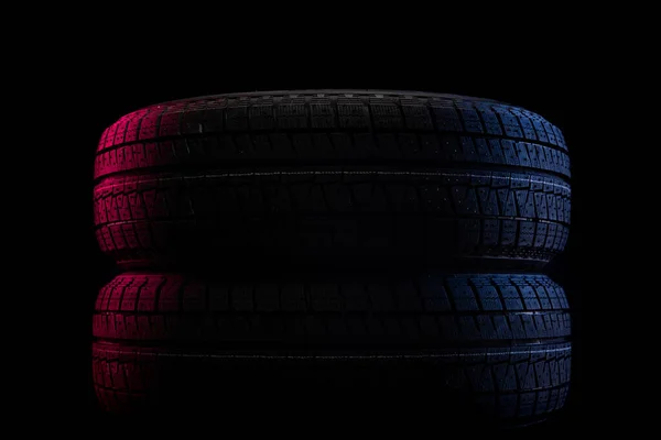 Dois pneus de inverno deitados um em cima do outro em um fundo preto — Fotografia de Stock