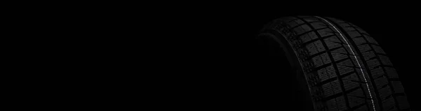 Fekete gumiabroncs téli futófelülettel fekete, stílusos háttéren közelkép — Stock Fotó