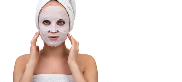 Une femme après une douche avec un masque cosmétique blanc sur le visage masse la peau autour des pommettes — Photo