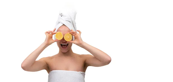 A cheerful middle-aged woman with well-groomed skin after a shower with a cut orange in her hands instead of eyes — Stock Photo, Image