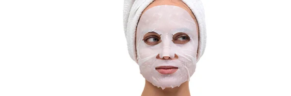 Duş aldıktan sonra yüzünün üzerinde örülmemiş kumaştan yapılmış beyaz bir kozmetik maskeyle bir kadının yakın plan portresi. — Stok fotoğraf