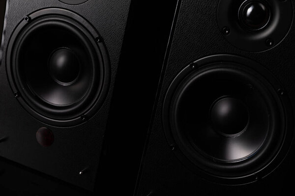 Black speaker system with piano lacquer and huge speakers on a black background.