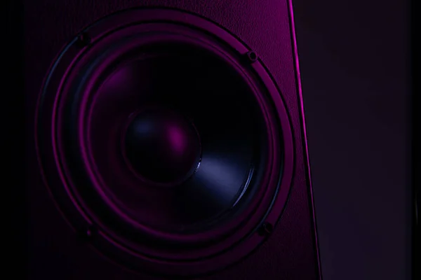 Великий динамік крупним планом на чорному фоні з фіолетово-фіолетовим освітленням крупним планом, відтворення музики на розкішній акустичній системі — стокове фото