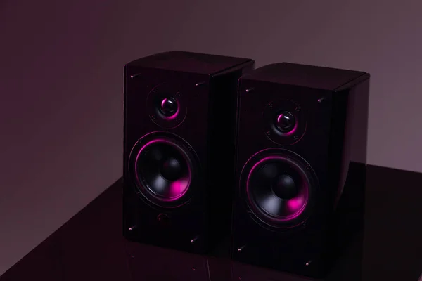Un par de altavoces para escuchar música sobre un fondo oscuro con retroiluminación morado-lila, monitores de estudio profesionales para un ingeniero de sonido —  Fotos de Stock