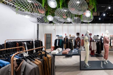 Bir gençlik mağazası fotoğrafı, kotlu, dış giyimli, ceketli, gömlekli, kazaklı, tişörtlü, kapüşonlu, pantolonlu, alışveriş merkezindeki erkekler ve kadınlar için şık ve şık kıyafetler. Bir mankenin üzerindeki giysi