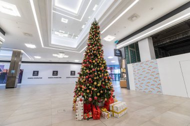 Minsk, Belarus - 25 Kasım 2021: Parlak topları ve hediyeleri alışveriş merkezinde kutularda olan yeşil bir Noel ağacının fotoğrafı. Noel ve Yeni Yıl
