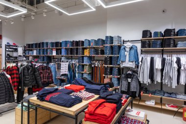 Minsk, Belarus - 25 Kasım 2021: Bir alışveriş merkezindeki kadın ve erkekler için pantolon, kot, ceket, tişört, kazak, kapüşon, pantalon