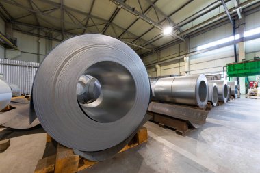 Metalik makine üretim hattının çatısındaki metal fayansların yakından çekilmiş fotoğrafı. Fabrikada soğuk çelik bobinler var.