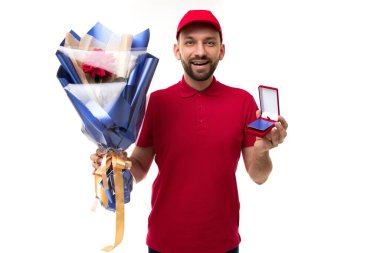 Elinde bir buket çiçek ve indirim kartıyla kurye elinde kırmızı üniformalı beyaz bir arka planda gülümsemeyle kameraya bakıyor.