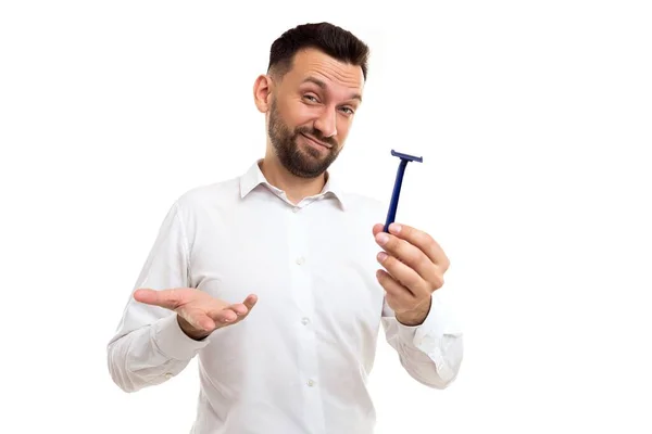 Ein Mann mit Bart hält ein Rasiermesser in den Händen und hebt verwirrt die Schultern — Stockfoto