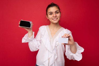 Moda kıyafetleri içinde genç, beyaz, hippi bir kadının portresi. Stüdyoda kırmızı duvarın yanında yalnız poz veren kaygısız seksi kadın. Doğal makyajlı pozitif bir model. Tutuluyor