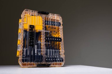 Arka planda sondaj delikleri ve metin için fotokopi alanı ile izole edilmiş tornavida için matkaplarla birlikte turuncu ve şeffaf kit kutusunun fotoğraf çekimi. Tamir ve inşaat konsepti. Araçlar kümesi