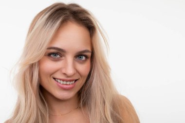 Çekici orta yaşlı sarışın, yüzünde bir gülümsemeyle beyaz arka plandaki kameraya bakıyor.