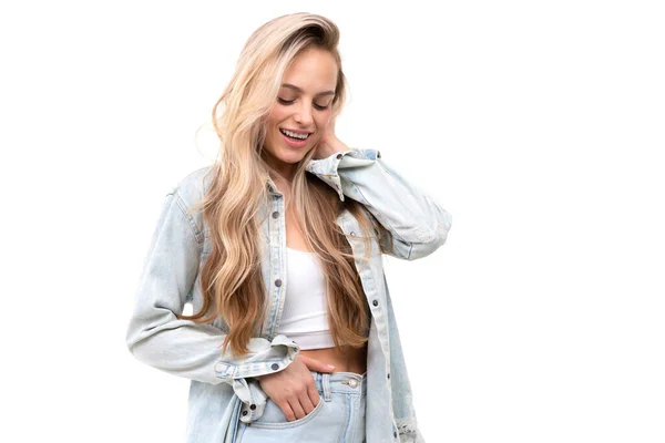 Flirty beautiful blonde on a white background in a light denim suit — Stockfoto