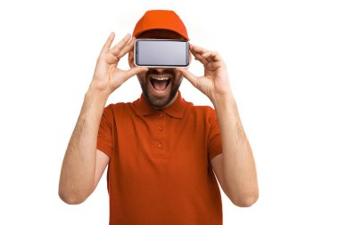 Teslimat kuryesi karizmatik gülümseme her iki elinde beyaz arka planda akıllı telefon tutar