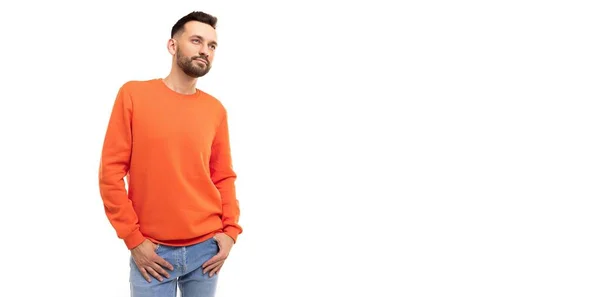 Ένας νεαρός άνδρας με πορτοκαλί πουλόβερ κοιτάζει στο πλάι σε λευκό φόντο. — Φωτογραφία Αρχείου