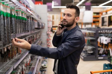 customer man in a hardware store chooses drills for a drill and screwdriver