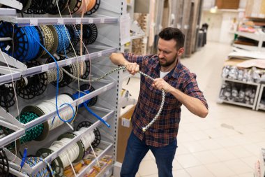 a customer in a hardware store checks the strength of a safety rope for climbing and high-altitude work