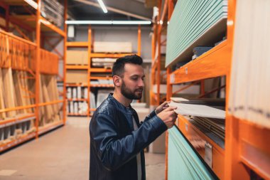 Hırdavatçıdaki adam kerestecinin sahibi. Evin onarımı için alçıpan seçiyor.