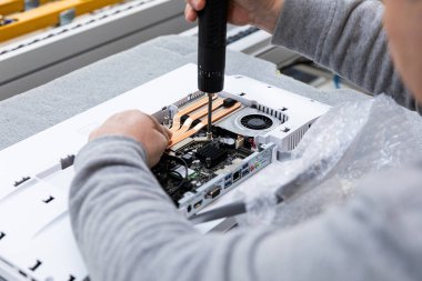 Monoblock montaj fabrikasındaki bir taşıma bandında bilgisayar monitör sistemi bloğu kuran bir adamın fotoğrafı. Modern yüksek teknoloji fabrikası