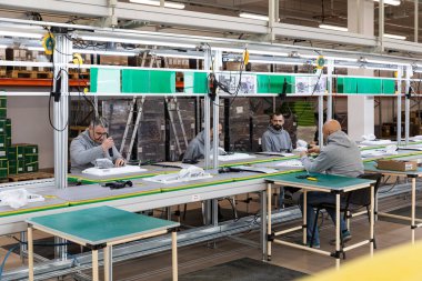 Minsk, Belarus - 15 Aralık 2021: Bilgisayarlar için monoblock montajı için kullanılan büyük bir fabrikanın fotoğrafı. Taşıyıcı banttaki erkek işçiler. Fabrika