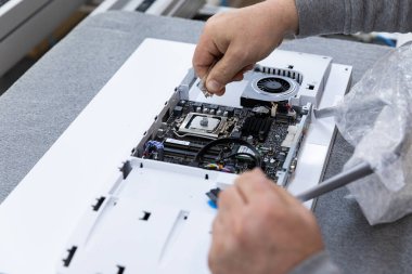 Monoblock montaj fabrikasındaki bir taşıma bandında bilgisayar monitör sistemi bloğu kuran adamın el fotoğrafı. Mühendis modern bir yüksek teknoloji fabrikasında çalışıyor.