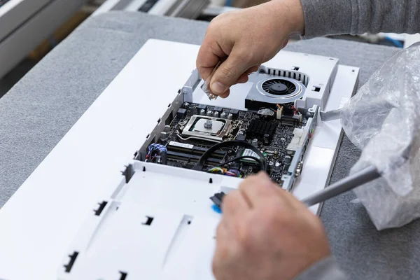 Monoblock montaj fabrikasındaki bir taşıma bandında bilgisayar monitör sistemi bloğu kuran adamın el fotoğrafı. Mühendis modern bir yüksek teknoloji fabrikasında çalışıyor.