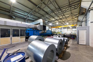 Çelik çatı oluşum makinesinin fotoğrafı. Metal kaplama çatı bobinleri için endüstriyel makine. Fabrika ve bitki arka planı