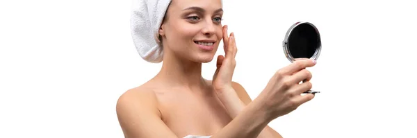 Een vrouw na een douche bewondert zichzelf in een kleine spiegel op een witte achtergrond — Stockfoto