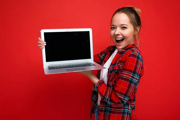 Photo de jeune jolie belle femme blonde souriante heureuse et positive en chemise rouge élégante. Sexy insouciante femme isolée sur fond de mur rouge en studio avec un espace vide pour le texte et — Photo