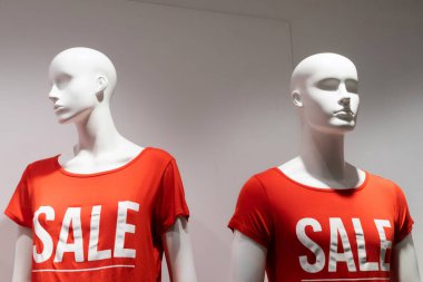 Üzerinde yazı indirimi olan kırmızı tişörtlü mankenler.