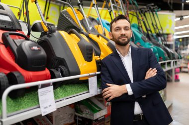 Bahçe gereçleri satan bir mağazada, geniş bir petrol ve elektrikli çim biçme makinesi yelpazesi olan bir vitrinin yanında.