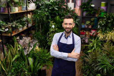 Saksı bitkileriyle çevrili çiçek deposu işçisi