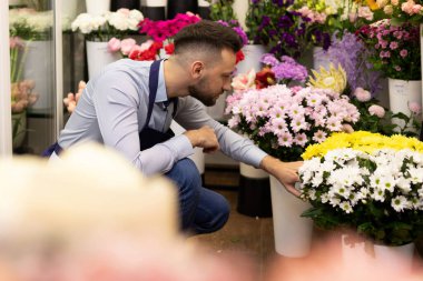 Çiçekçi dükkanında satıcı arka planda buketli raflara karşı