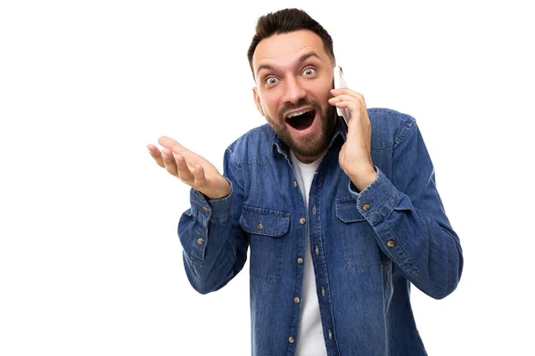 Surprisedly charismatic man with open mouth and wide eyes speaks on the phone gesturing with his hands — Stock Photo, Image