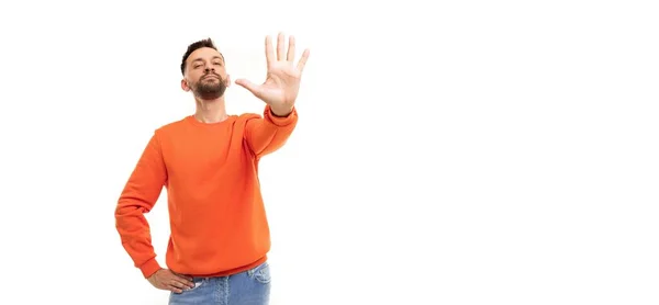 Un hombre en un jersey naranja sobre un fondo blanco extiende su palma hacia adelante con cinco dedos —  Fotos de Stock