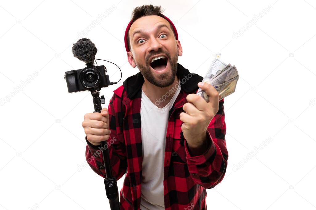 happy blogger streamer with a camera and a wad of money in his hands laughs emotionally looking at the camera with a smile on his face
