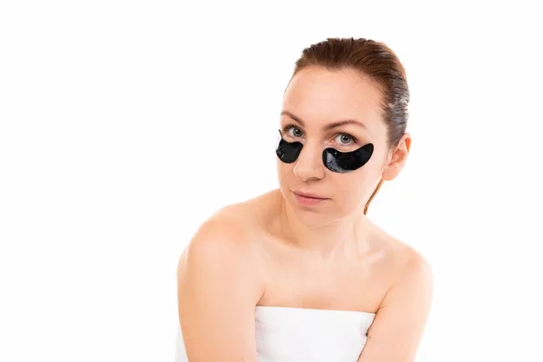 Young woman in a towel after cosmetic procedures on the background of a white wall with looking at the camera — Stock Photo, Image