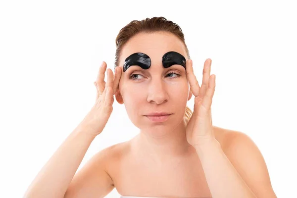 Young woman fooling around sticking cosmetic patches on her eyebrows during cosmetic procedures — Stock Photo, Image