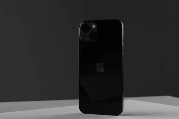 Nieuwe moderne mobiele telefoon iPhone 13 in zwarte kleur tegen een grijze muur — Stockfoto