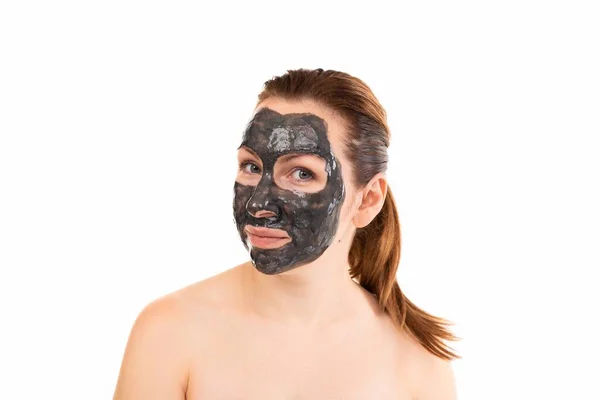 Young woman after a shower with a black cosmetic mask on her face made of clay — Stock Photo, Image