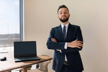 Mavi takım elbiseli bir şirket yöneticisi dizüstü bilgisayar ekranı gösteriyor