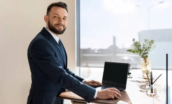 company manager with a smile looks at the camera demonstrates the screen of a laptop