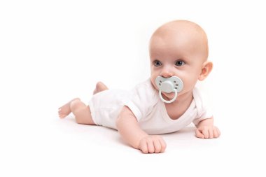 Ağzında emzik olan bebek beyaz izole bir arka planda yatıyor.