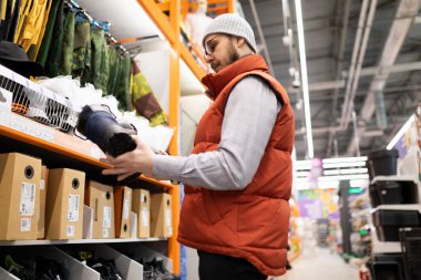 Nalbur müşterisi çarpışma korumalı bir inşaat alanında çalışmak için ayakkabı seçer