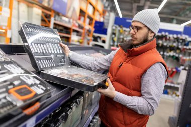 Alet inşa malzemeleri mağazasındaki bir müşteri yeni anahtar ve soketler seti seçer