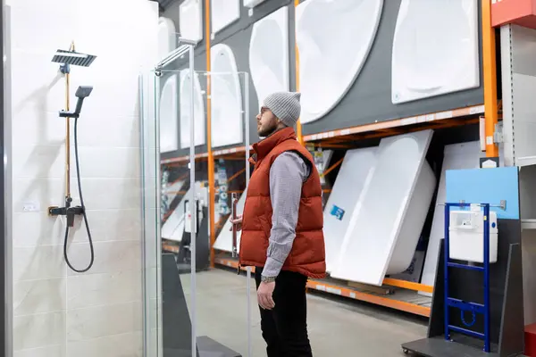 a customer in a plumbing store chooses a shower cabin and a bathtub