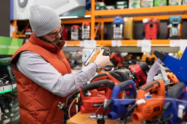 a customer in a non-power tool store chooses a new electric jigsaw for himself, the concept of a professional carpenter