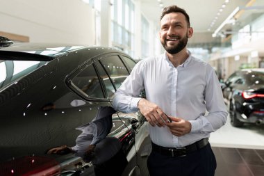 Bir araba galerisinde yüzünde gülümseme olan karizmatik bir adam yeni bir araba almayı hayal ediyor.